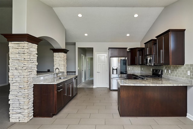 9305 Sugar Creek Cir, West Des Moines, IA 50266 - kitchen with appliances with stainless steel finishes, vaulted ceiling, ornate columns, a peninsula, and decorative backsplash