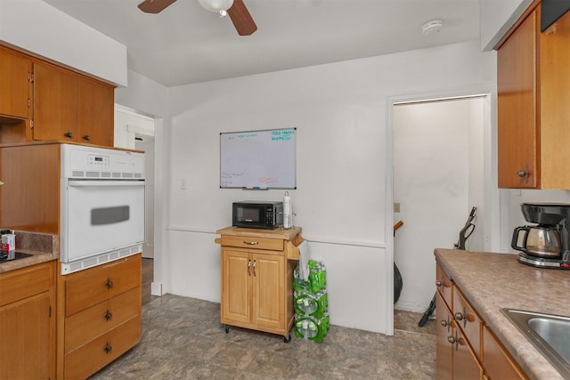2904 Shadyoak Dr, Des Moines, IA 50310 - kitchen featuring oven, black microwave, a ceiling fan, brown cabinets, and light countertops