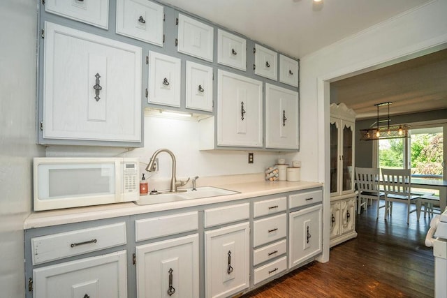 310 E 19th St S, Newton, IA 50208 - kitchen with white microwave, light countertops, dark wood-style floors, crown molding, and decorative light fixtures