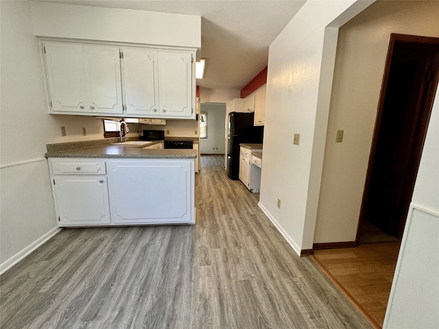 4425 Amick Ave, Des Moines, IA 50310 - kitchen with freestanding refrigerator, light wood-type flooring, white cabinets, a peninsula, and dark countertops
