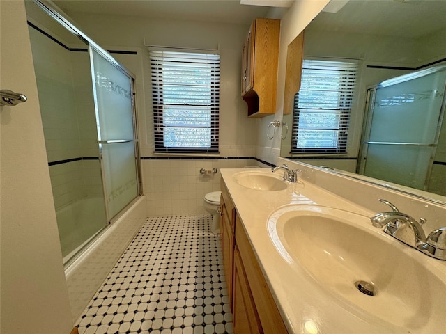 4425 Amick Ave, Des Moines, IA 50310 - full bath featuring healthy amount of natural light, double vanity, combined bath / shower with glass door, tile walls, and tile patterned flooring