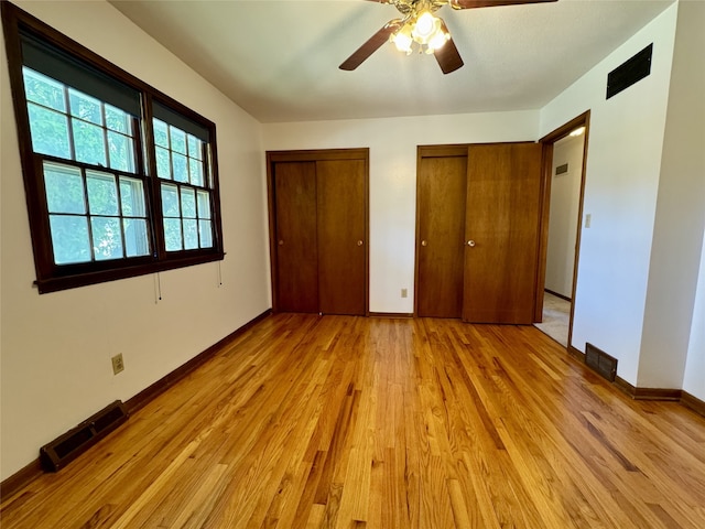 4425 Amick Ave, Des Moines, IA 50310 - unfurnished bedroom with two closets, light wood-type flooring, and ceiling fan