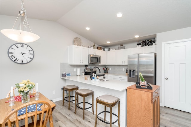 1165 Locust St, Waukee, IA 50263 - kitchen with stainless steel appliances, a peninsula, light wood finished floors, light countertops, and vaulted ceiling