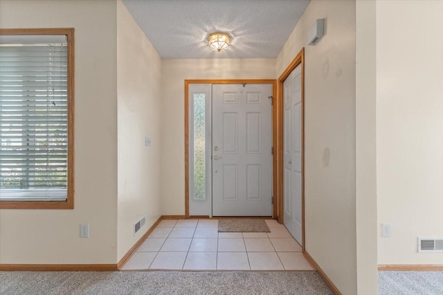 130 NW Georgetown Blvd Unit 4, Ankeny, IA 50023 - entryway featuring a textured ceiling, light tile patterned floors, and light colored carpet