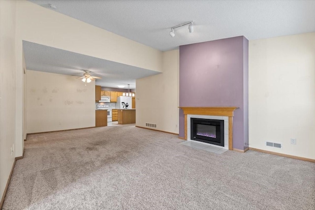 130 NW Georgetown Blvd Unit 4, Ankeny, IA 50023 - unfurnished living room featuring light carpet, track lighting, a tile fireplace, and ceiling fan