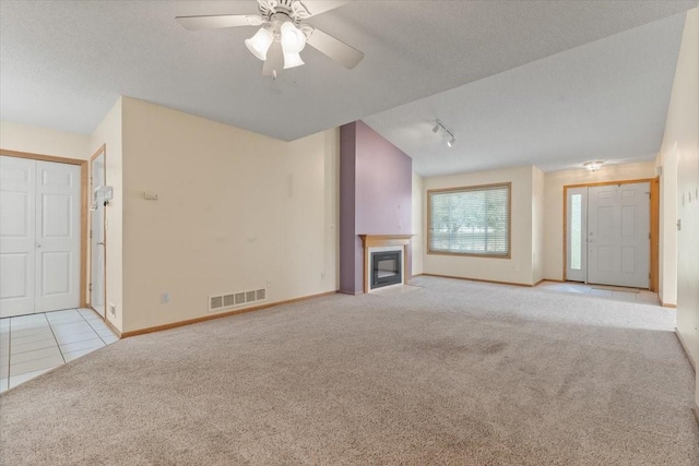 130 NW Georgetown Blvd Unit 4, Ankeny, IA 50023 - unfurnished living room with carpet, a glass covered fireplace, rail lighting, ceiling fan, and tile patterned flooring