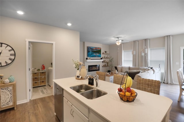 70 Prairie Bluff Dr, Waukee, IA 50263 - kitchen with open floor plan, a glass covered fireplace, dark wood-style floors, dishwasher, and a center island with sink