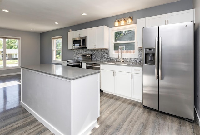 1808 Payton Ave, Des Moines, IA 50315 - kitchen with stainless steel appliances, a center island, light wood-style flooring, white cabinets, and recessed lighting