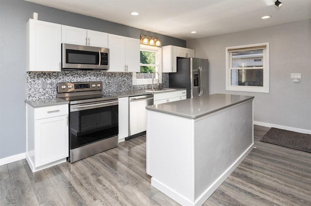 1808 Payton Ave, Des Moines, IA 50315 - kitchen featuring appliances with stainless steel finishes, backsplash, white cabinetry, wood finished floors, and recessed lighting