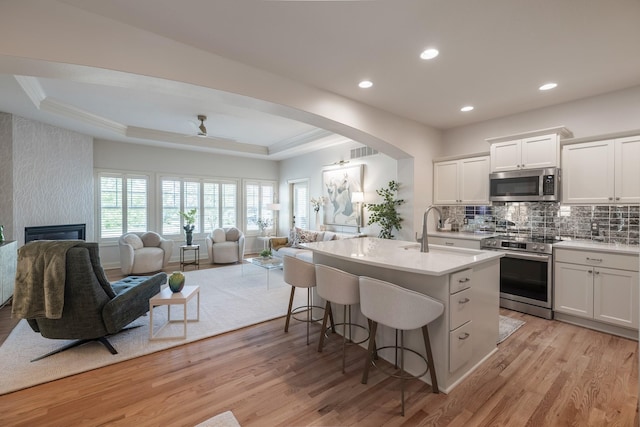 255 S 41st St Unit 171, West Des Moines, IA 50265 - kitchen featuring appliances with stainless steel finishes, open floor plan, light wood-style floors, a kitchen bar, and light countertops