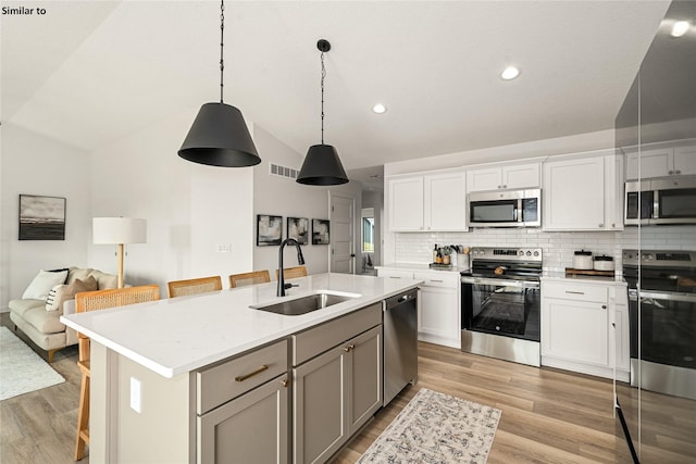 1620 NW Jackson Dr, Ankeny, IA 50023 - kitchen with stainless steel appliances, vaulted ceiling, light wood finished floors, a kitchen island with sink, and open floor plan