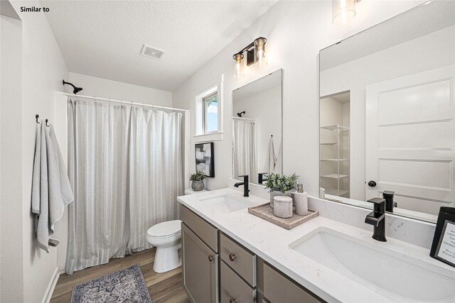 1620 NW Jackson Dr, Ankeny, IA 50023 - bathroom with wood finished floors, double vanity, a shower with shower curtain, and a textured ceiling