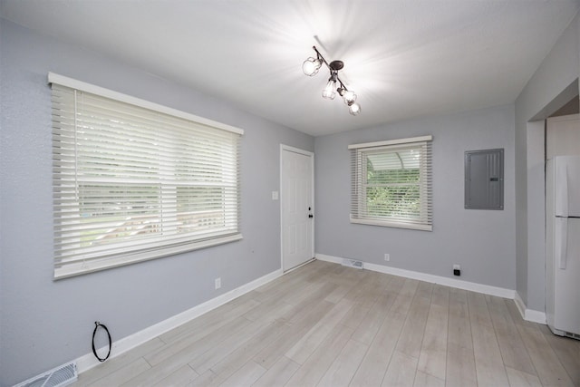 3416 Garfield Ave, Des Moines, IA 50317 - unfurnished dining area featuring electric panel, light wood-style flooring, and a chandelier