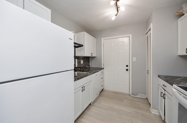 3416 Garfield Ave, Des Moines, IA 50317 - kitchen with white appliances, light wood-style floors, white cabinets, dark countertops, and tasteful backsplash
