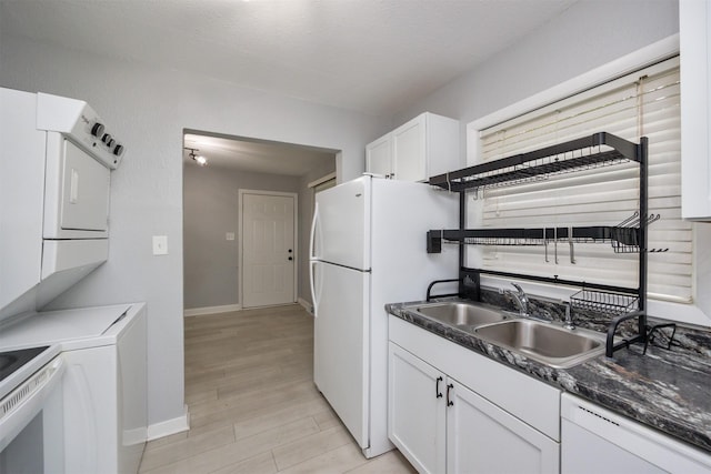 3416 Garfield Ave, Des Moines, IA 50317 - kitchen featuring white appliances, estacked washer and dryer, white cabinets, dark countertops, and light wood-type flooring