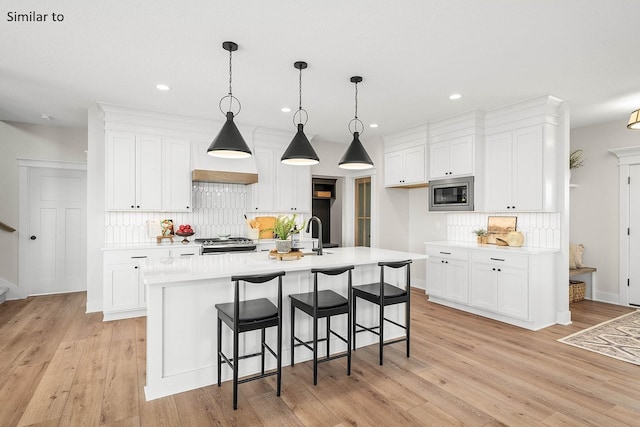 2281 Green Leaf Cir, Norwalk, IA 50211 - kitchen featuring stainless steel microwave, tasteful backsplash, light countertops, white cabinetry, and recessed lighting