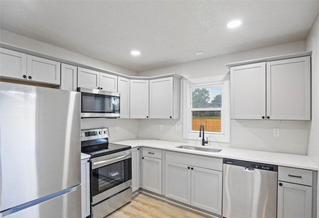 2420 E 37th St, Des Moines, IA 50317 - kitchen with appliances with stainless steel finishes, light countertops, recessed lighting, light wood finished floors, and gray cabinetry