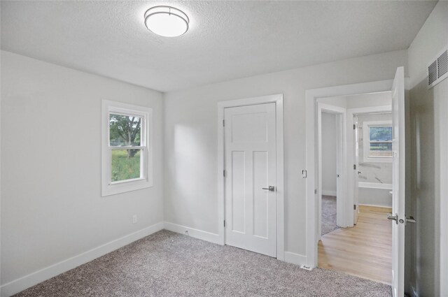2420 E 37th St, Des Moines, IA 50317 - unfurnished bedroom featuring a textured ceiling and light colored carpet