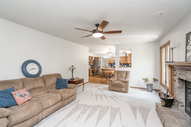 130 SW Meadowlark Ct, Ankeny, IA 50023 - living room featuring a ceiling fan, a fireplace, light colored carpet, and a chandelier