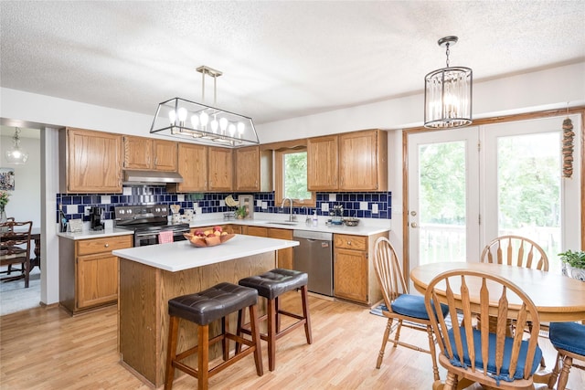 130 SW Meadowlark Ct, Ankeny, IA 50023 - kitchen with stainless steel appliances, under cabinet range hood, backsplash, a chandelier, and a textured ceiling