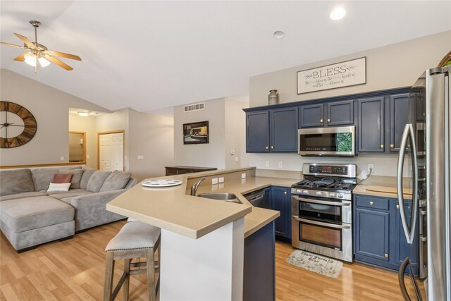 1701 2nd Ave SW, Altoona, IA 50009 - kitchen with stainless steel appliances, a peninsula, blue cabinetry, open floor plan, and light wood-style flooring
