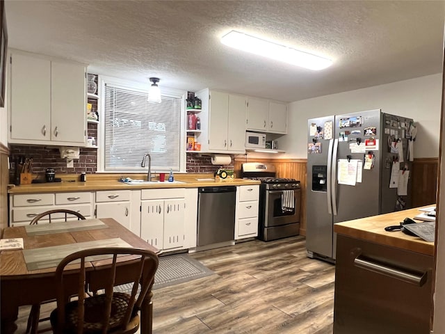 109 E Jackson St, Panora, IA 50216 - kitchen with open shelves, stainless steel appliances, a textured ceiling, white cabinets, and wood finished floors