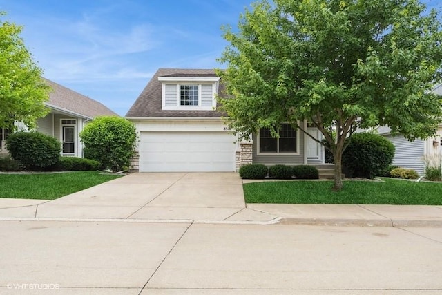 8318 Boulder Dr, West Des Moines, IA 50266 - view of property hidden behind natural elements with concrete driveway, stone siding, a front lawn, and an attached garage