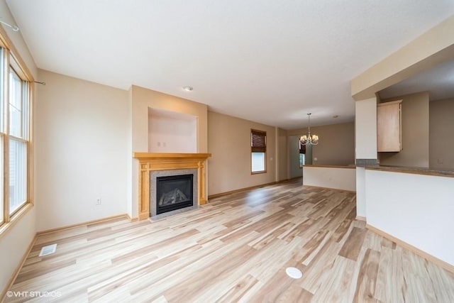 8318 Boulder Dr, West Des Moines, IA 50266 - unfurnished living room featuring a chandelier, light wood-type flooring, and a fireplace with flush hearth