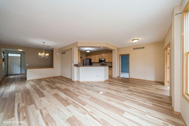 8318 Boulder Dr, West Des Moines, IA 50266 - unfurnished living room featuring light wood-type flooring and a chandelier