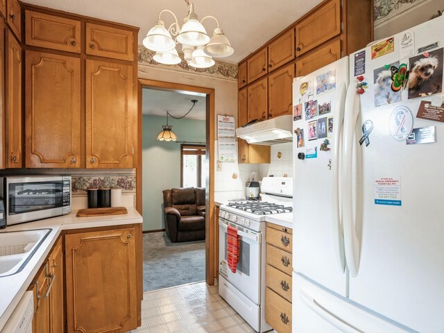 2400 Farwell Rd, Des Moines, IA 50317 - kitchen featuring white appliances, under cabinet range hood, a chandelier, light countertops, and brown cabinets
