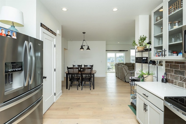 309 NW Beechwood Dr, Grimes, IA 50111 - kitchen with appliances with stainless steel finishes, light wood-style flooring, white cabinetry, glass insert cabinets, and recessed lighting