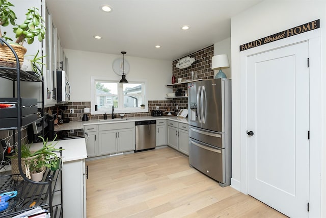 309 NW Beechwood Dr, Grimes, IA 50111 - kitchen featuring appliances with stainless steel finishes, tasteful backsplash, light wood-style flooring, light countertops, and recessed lighting