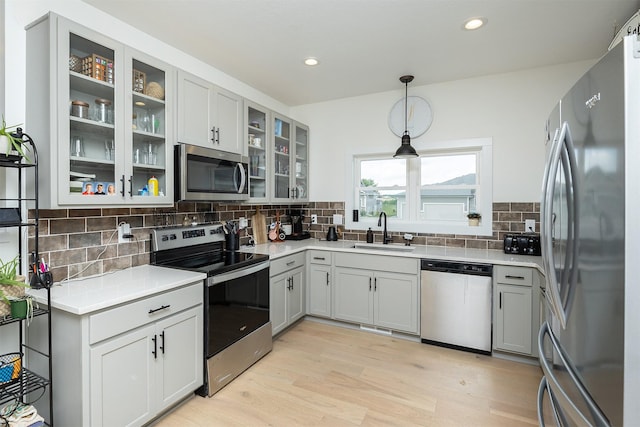 309 NW Beechwood Dr, Grimes, IA 50111 - kitchen featuring appliances with stainless steel finishes, light wood-type flooring, backsplash, light countertops, and decorative light fixtures