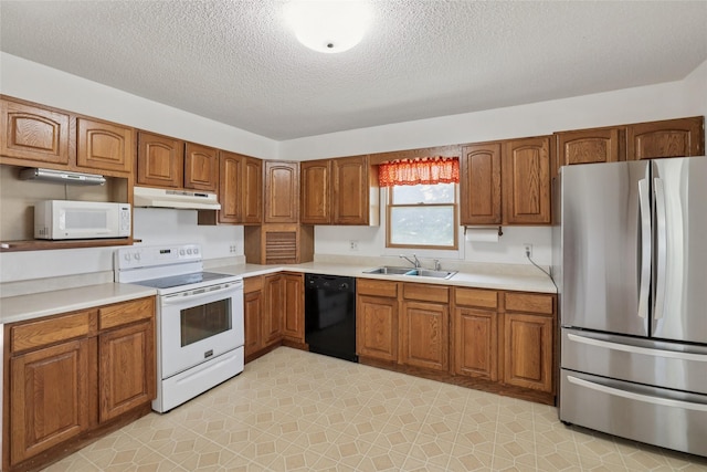 7404 Sioux Ave, Reasnor, IA 50232 - kitchen featuring white appliances, under cabinet range hood, brown cabinets, and a textured ceiling