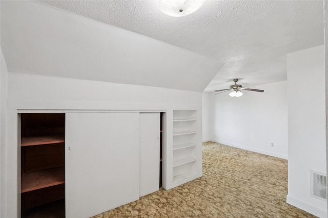 7404 Sioux Ave, Reasnor, IA 50232 - bonus room featuring carpet flooring, built in features, a ceiling fan, vaulted ceiling, and a textured ceiling