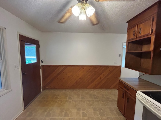 7116 Maple Dr, Urbandale, IA 50322 - kitchen with a wainscoted wall, a textured ceiling, a ceiling fan, wood walls, and light floors