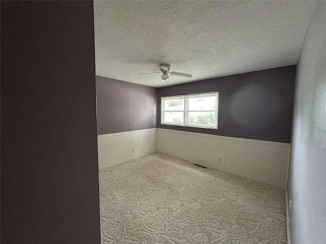 7116 Maple Dr, Urbandale, IA 50322 - unfurnished room featuring a wainscoted wall, ceiling fan, a textured ceiling, and carpet flooring
