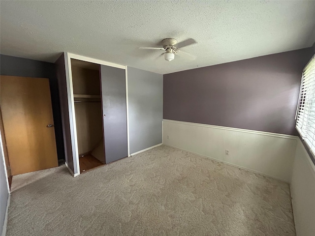 7116 Maple Dr, Urbandale, IA 50322 - unfurnished bedroom featuring a textured ceiling, carpet, a closet, wainscoting, and ceiling fan