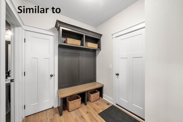 3217 NW Prescott Ct, Grimes, IA 50111 - mudroom featuring wood finished floors and a textured ceiling