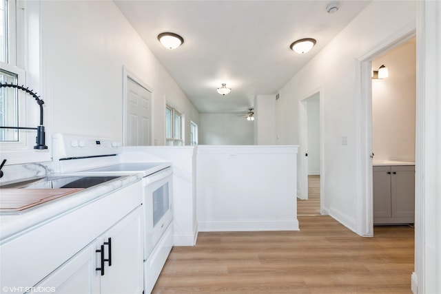 1547 13th St, Des Moines, IA 50314 - kitchen with white electric stove, light wood-style floors, light countertops, white cabinetry, and a ceiling fan