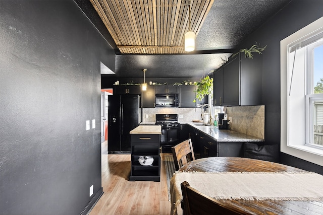 1315 Bundy St, Des Moines, IA 50315 - kitchen featuring black appliances, dark cabinets, light wood-type flooring, backsplash, and pendant lighting