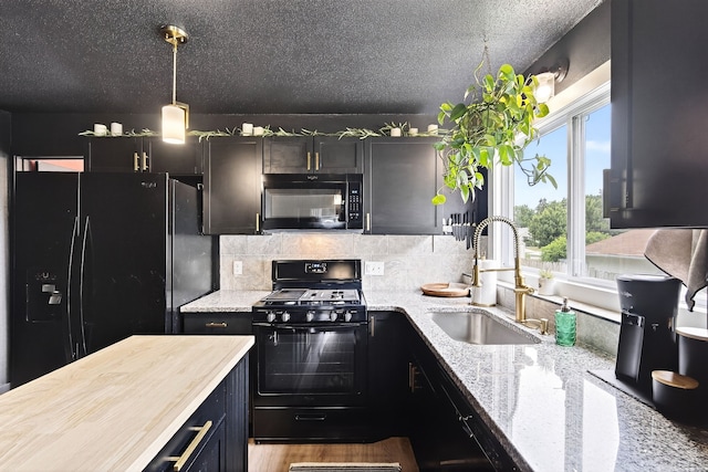 1315 Bundy St, Des Moines, IA 50315 - kitchen with black appliances, backsplash, hanging light fixtures, a textured ceiling, and light stone countertops