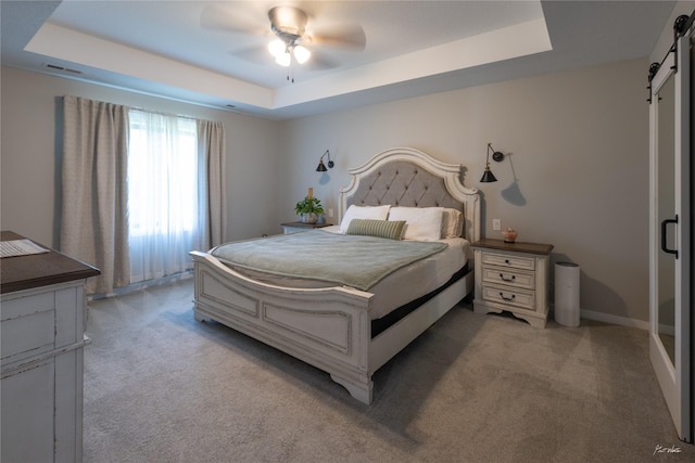 807 W Orchard Ave, Indianola, IA 50125 - bedroom featuring a barn door, a tray ceiling, light carpet, and a ceiling fan