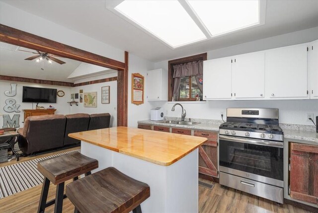 407 E Mckinney St, Runnells, IA 50237 - kitchen with stainless steel range with gas stovetop, open floor plan, wood finished floors, vaulted ceiling, and a kitchen island