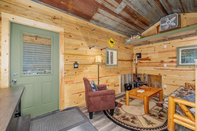 407 E Mckinney St, Runnells, IA 50237 - living area featuring a wood stove, vaulted ceiling, wood ceiling, wooden walls, and wood finished floors