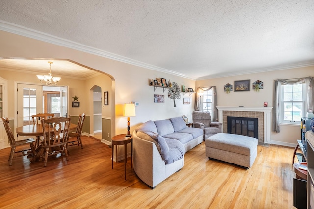 1209 Edgemont St, Des Moines, IA 50315 - living room featuring light wood-type flooring, ornamental molding, arched walkways, a textured ceiling, and a chandelier