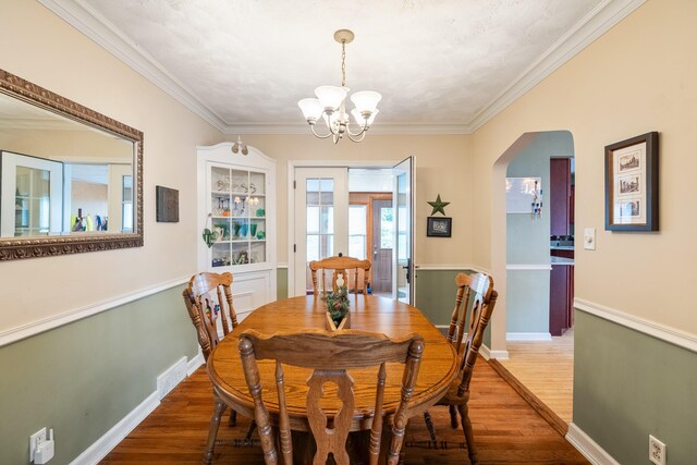 1209 Edgemont St, Des Moines, IA 50315 - dining area with wood finished floors, arched walkways, a chandelier, and crown molding
