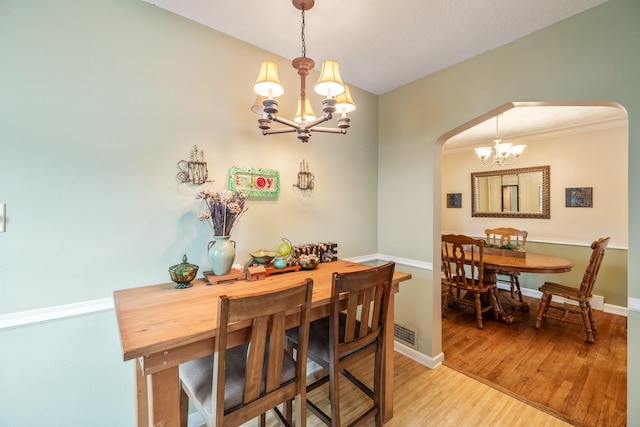 1209 Edgemont St, Des Moines, IA 50315 - dining space featuring arched walkways, a chandelier, and light wood-style floors