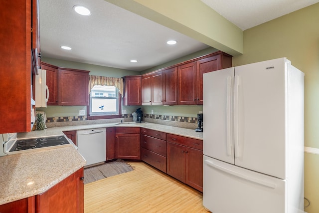 1209 Edgemont St, Des Moines, IA 50315 - kitchen with white appliances, light wood-style flooring, light countertops, dark brown cabinets, and recessed lighting