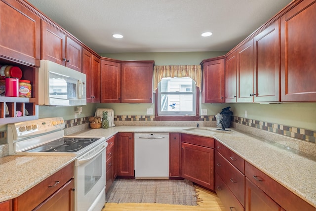 1209 Edgemont St, Des Moines, IA 50315 - kitchen featuring white appliances, reddish brown cabinets, recessed lighting, light wood-style flooring, and light stone countertops